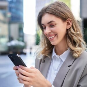 Portrait of smiling businesswoman chat in app, looking at smartphone with pleased face, order