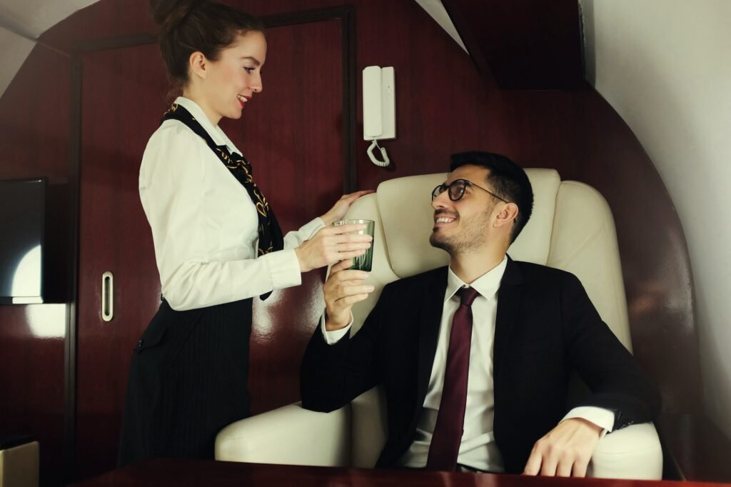 Young billionaire travelling first class, flight attendant is bringing him glass of champagne